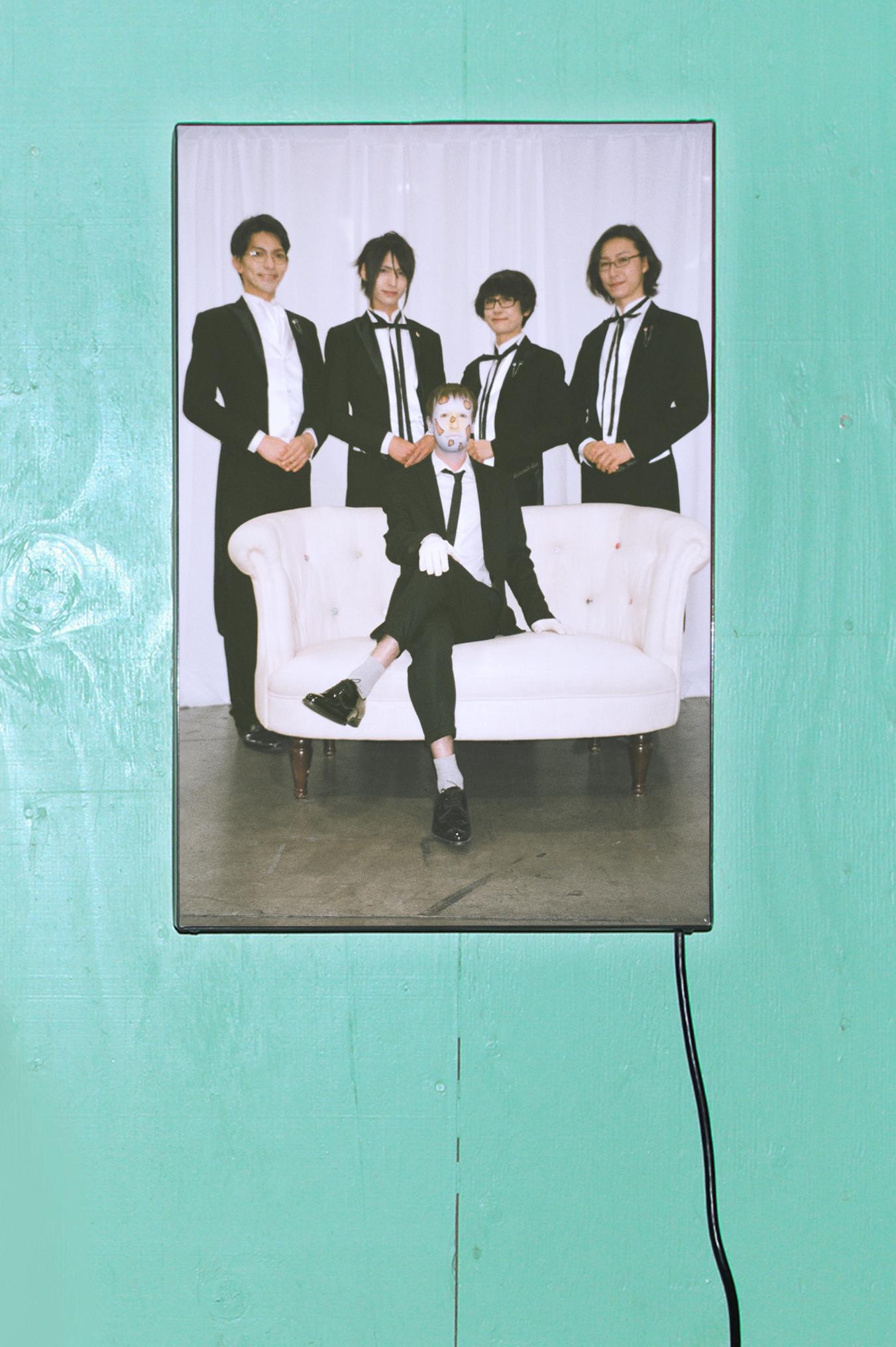 Photohrpahic lightbox print of Jesse surrounded by butlers hung on a teal wooden background 